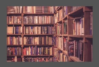 Image shows wall to wall books on shelves in a library or bookshop