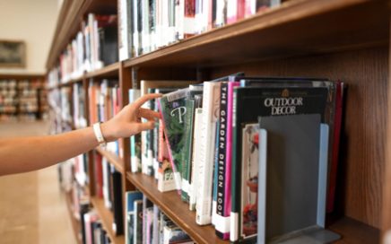 Person pulling a book from a library shelf